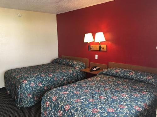 two beds in a hotel room with red walls at Relax Inn West Amarillo Medical Center in Amarillo