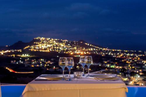 two wine glasses on a table with a view of the city at Carpe Diem Santorini in Pirgos