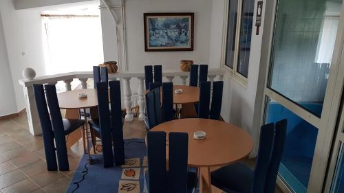 a dining room with two tables and blue chairs at Guest House Luxotel in Zrenjanin