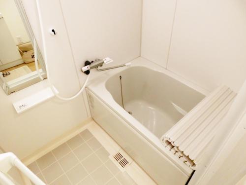 a white bath tub in a bathroom with a mirror at Guesthouse TOHO in Nagoya