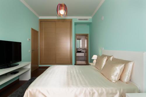 sypialnia z białym łóżkiem i telewizorem w obiekcie Porto de Mos Golf & Beach B&B AL-40312 w Lagosie