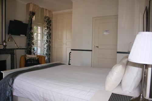 a bedroom with a white bed and a lamp at Château de la Grange Fort in Issoire