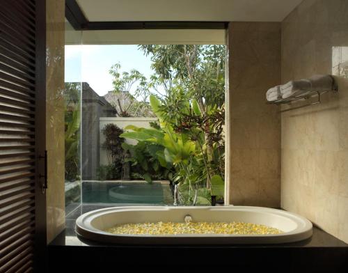 a large bath tub in a room with a window at Mahagiri Villas Sanur in Sanur