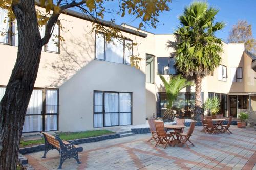 a house with a courtyard with chairs and a table at Auckland Airport Kiwi Hotel in Auckland