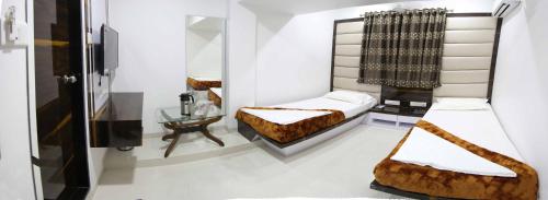 a bedroom with two beds and a mirror at Hotel Fantacee in Navi Mumbai