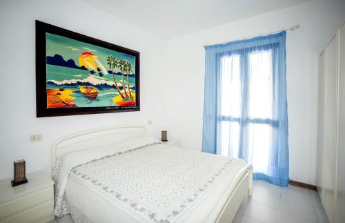 a bedroom with a white bed with a painting on the wall at Cav Brunella in Castiglione della Pescaia