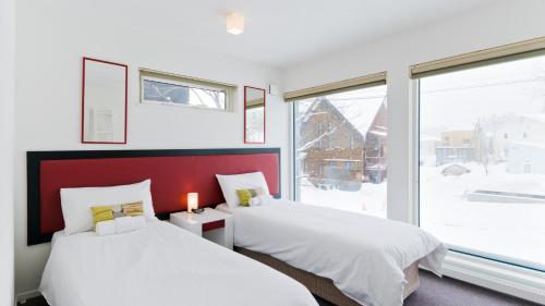 two beds in a room with a large window at SeiSei in Niseko
