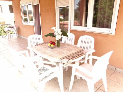 a table with white chairs and a table with fruit on it at Apartments Jerković in Stari Grad