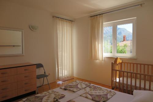 a bedroom with a crib and a window at Apartments Kovacic in Omiš