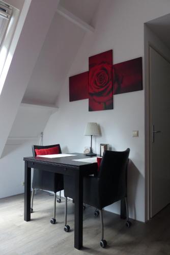 ディーレンにあるB&B Onder de rode beukのデスク(椅子付)が備わります。壁に赤いバラが飾られています。