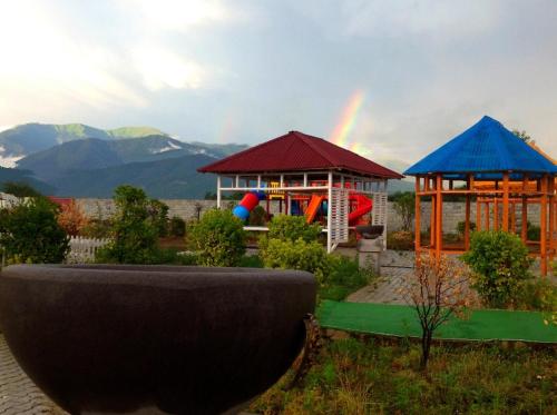 a rainbow in the sky over two play structures at Paradise Investment Resort in Tʼelavi