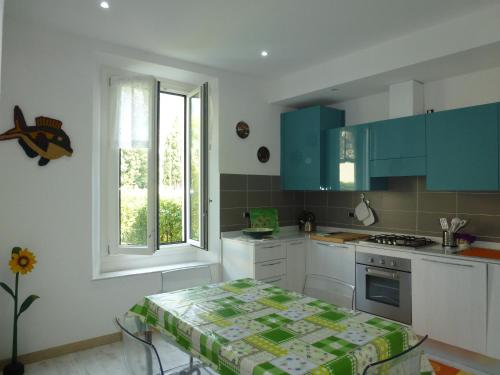 uma cozinha com armários azuis e uma mesa em Casa Giardino em Gravedona