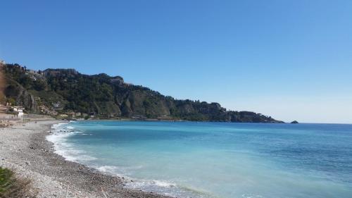 a beach with blue water and a mountain at Villa Laura Apartment in Giardini Naxos