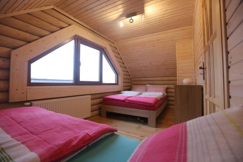 a small room with two beds and a window at Sosnowe Domki in Rewal