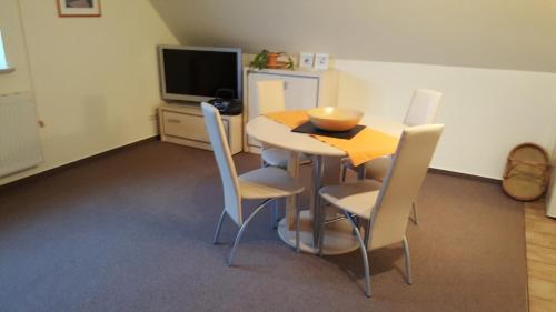 a dining room with a table and chairs and a television at Ferienwohnungen An der Ostsee in Wittenbeck