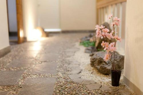 a stone walkway with pink flowers in a vase at Shin Okubo Sekitei in Tokyo