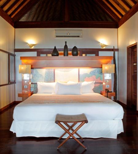 a bedroom with a large white bed with a wooden headboard at Sofitel Kia Ora Moorea Beach Resort in Maharepa