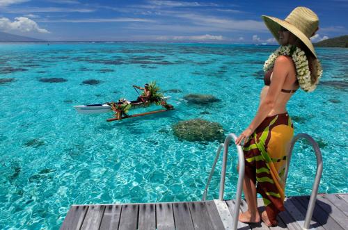 a woman in a hat sitting on a boat in the water at Sofitel Kia Ora Moorea Beach Resort in Maharepa