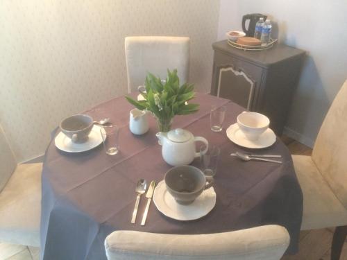 een eettafel met een blauw tafelkleed en kopjes bij La Chambre Montbrault in Fleurigné