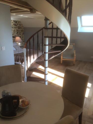 - un escalier en colimaçon dans un salon avec une table dans l'établissement La Chambre Montbrault, à Fleurigné
