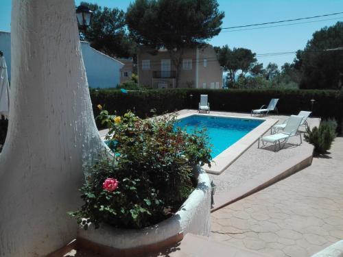 a swimming pool with two chairs and flowers in a yard at Casa Garonda in Cala Pi