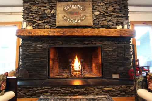 a stone fireplace with a fire in it at Trailside Inn in Killington
