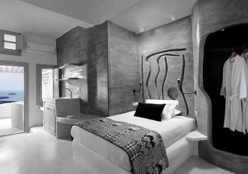 een slaapkamer met een groot bed en een badkamer bij Tholos Resort in Imerovígli