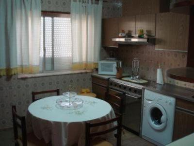 a kitchen with a white table and chairs and a table and a kitchen with at Vivenda Atlantico in Vila Praia de Âncora