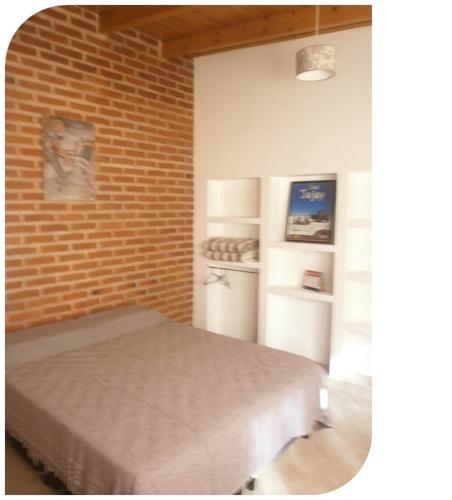 Pokój z łóżkiem i ceglaną ścianą w obiekcie Hostal Centenario w mieście El Carmen