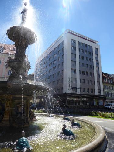 Ein Brunnen in einer Stadt, in der Leute spielen. in der Unterkunft Hotel Fleur-de-Lys in La Chaux-de-Fonds