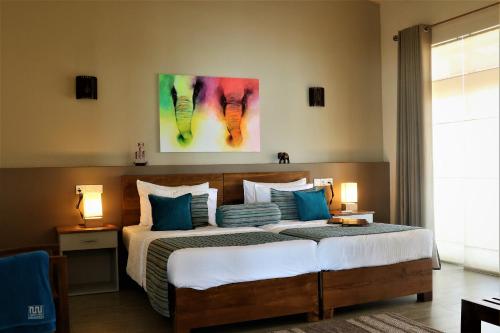 a bedroom with a large bed with a painting on the wall at Twenty-Two Weligambay in Weligama