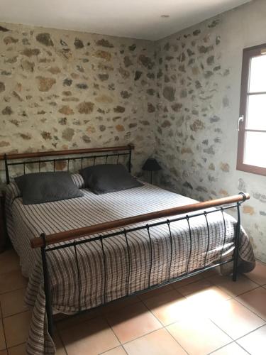 Écurie De Cucugnan في كوكونيان: سرير في غرفة بجدار حجري