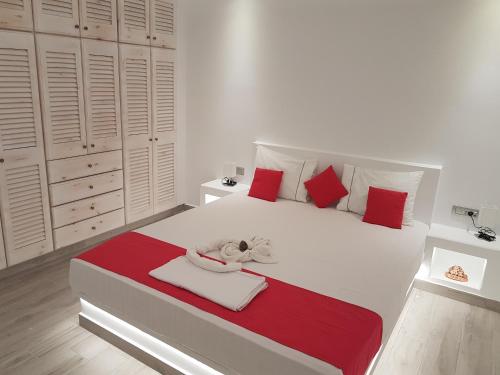 a white bedroom with a large white bed with red pillows at Casa Bella in Kamari