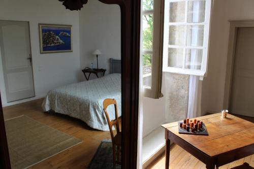 a bedroom with a bed and a table and a window at L'Ancien Couvent Cahuzac in Cahuzac