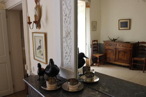 a room with a mirror and a table with cups and birds on it at L'Ancien Couvent Cahuzac in Cahuzac