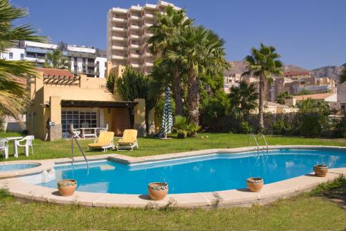 una piscina en un patio con palmeras y un edificio en Villa los Alamos, en Aguadulce