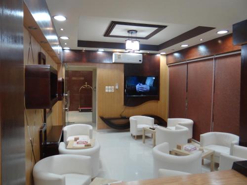 een wachtkamer met witte stoelen en een tv bij Royal Home Furnished Apartments in Wadi ad-Dawasir