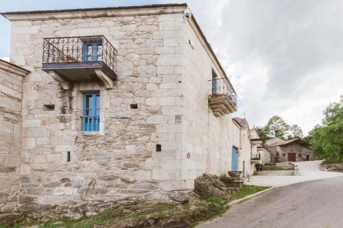 an old stone building with two balconies and a street at Pazo da Pena Manzaneda in Manzaneda