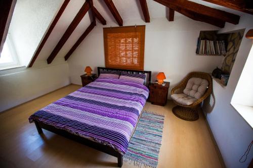 a bedroom with a large bed and a chair at Holiday Home Kvarantan in Veliki Drvenik