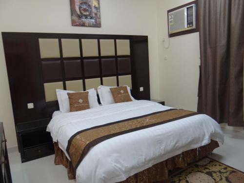 a bedroom with a large bed with a large headboard at Royal Home Furnished Apartments in Wadi Al Dawasir