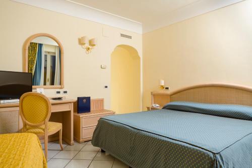a bedroom with a bed and a desk and a television at Hermitage Resort & Thermal Spa in Ischia