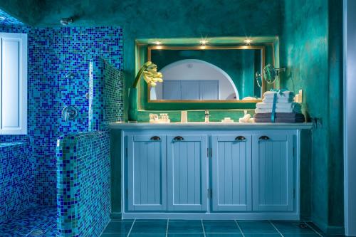 a blue bathroom with a sink and a mirror at Astra Suites in Imerovigli