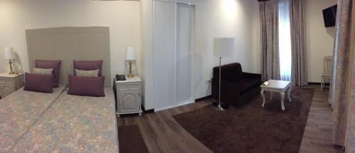 a room with a bed and a chair and a couch at Hotel Central Jardim in Geres