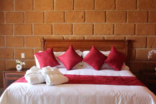a bed with red and white pillows and a brick wall at Hotel Boutique La Herencia in Tequisquiapan