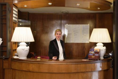 a woman sitting at a desk with two lamps at Hotel Morchio Mhotelsgroup in Diano Marina