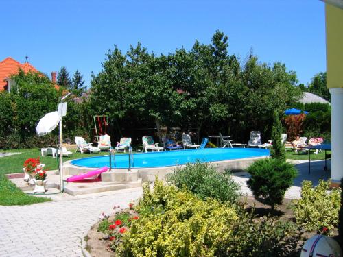 a swimming pool in a yard with chairs and trees at Barbara Wellness Pension in Keszthely