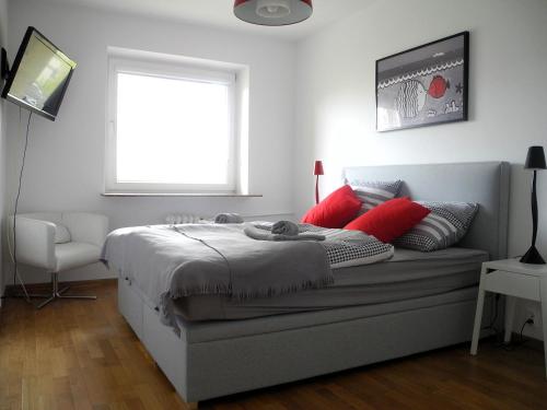 グディニャにあるApartament Redłowo Rybkiのベッドルーム1室(赤い枕のベッド1台、窓付)