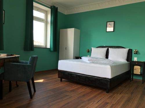 a bedroom with green walls and a bed and a chair at SmartHotel Mystique Self check-in in Bad Homburg vor der Höhe