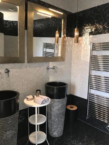 a bathroom with two stools and a sink and mirrors at Un Moment à la Campagne in Pleuven