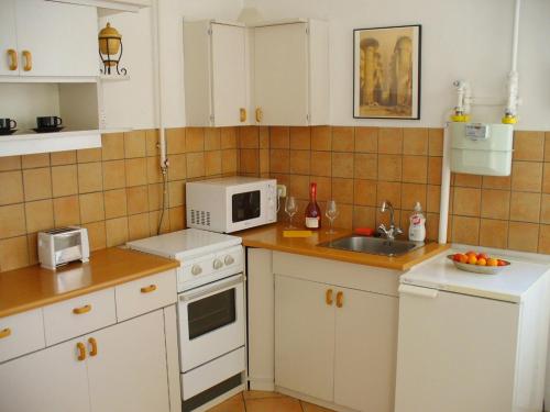 eine Küche mit weißen Schränken, einer Spüle und einer Mikrowelle in der Unterkunft Castle Area Apartment in Budapest